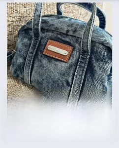 Detail der blauen Vintage-Jeans-Handtasche mit braunem Lederpatch und silbernem Metallstab