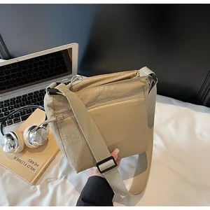 Detailed view of khaki nylon crossbody bag with multi-layer zippers and adjustable strap