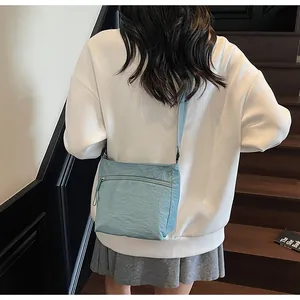 Detail of light blue pleated nylon crossbody bag with adjustable strap on a model