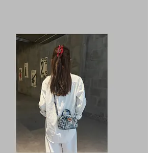Nahaufnahme einer blauen Denim-Boston-Tasche mit Schultergurt, getragen von einem Modell