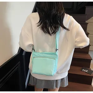 Close-up of mint green nylon crossbody bag with adjustable strap worn by a model