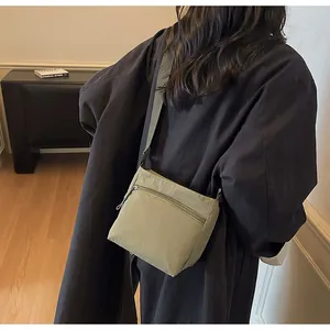 Close-up of olive green nylon crossbody bag showing adjustable strap and zipper pocket