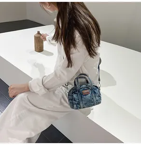 Detailaufnahme einer Mini-Umhängetasche aus blauem Denim mit braunem Logo und Trageriemen
