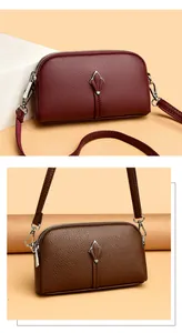 Détail de sacs à bandoulière en cuir bordeaux et marron avec décor de pétales métalliques