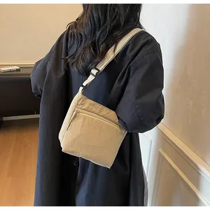 Model wearing beige nylon crossbody bag showing the adjustable strap and side profile detail
