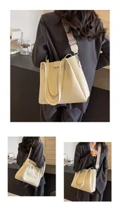 Detail of beige pebble leather tote bag featuring a decorative wide fabric strap