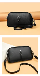 Gros plan du sac bandoulière en cuir noir grainé avec double fermeture éclair et boucle argent