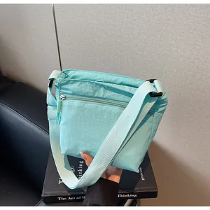 Detail of mint green nylon crossbody bag showing wide strap and front zipper pocket