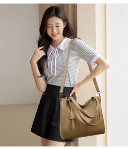 Brown litchi grain tote bag shown on model with adjustable strap and tassel detail