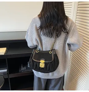Detail of black pleated crossbody bag featuring a vintage gold clasp and chain strap