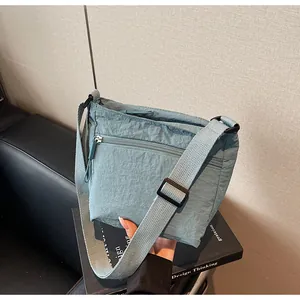 Detailed shot of grey-blue nylon crossbody bag with adjustable strap and front pocket