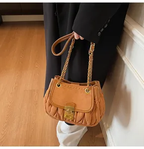 Detail of caramel suede shoulder bag featuring pleated texture and metallic buckle closure