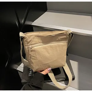 Macro shot of khaki nylon messenger bag with smooth zippers on grey stairs