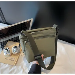 Detail of olive green nylon crossbody bag with zipper pocket and wide adjustable strap