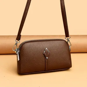 Détail de l'ornement feuille argentée et cuir grainé de ce sac bandoulière marron foncé