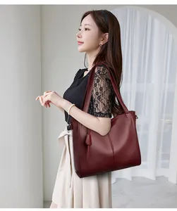 Detail of burgundy pebbled leather shoulder bag with embossed logo and chic charm