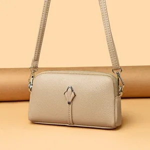Détail du sac bandoulière beige minimaliste avec texture litchi et boucle métallique florale