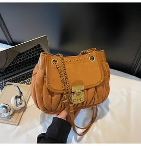 Detail of brown pleated suede shoulder bag with metal buckle and gold rivet accents
