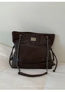 Detailed shot of dark brown retro tote bag with silver chain strap and leather texture