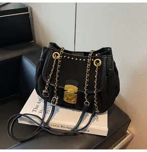 Detail of black quilted shoulder bag with golden chain strap and metallic push-lock closure