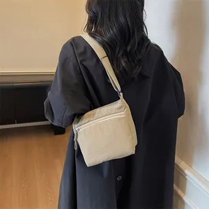 Minimalist beige nylon crossbody bag with wide shoulder strap for casual daily use