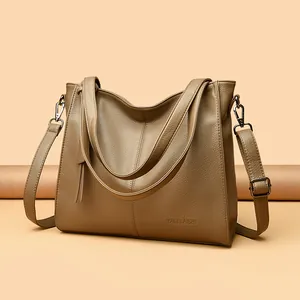 Detail of khaki leather tote bag featuring fine lychee texture and metallic strap hardware