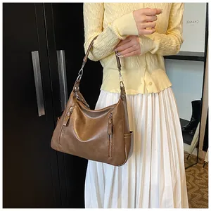 Detail of dark brown leather tote with vertical zippers and side pocket on shoulder