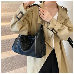 Detail of black tote bag with dual silver zippers and side pocket on a model