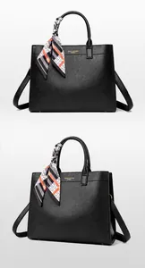 Dettaglio della borsa tote in pelle nera con logo dorato e foulard di seta decorativo