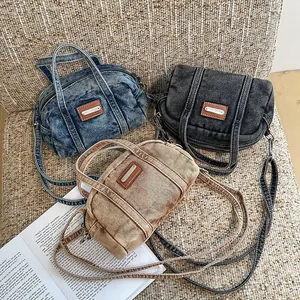 Drei Farben von Denim-Kissen-Umhängetaschen auf strukturiertem Stoff mit Buchdeko