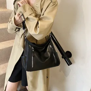 Fashionable black leather tote bag for women shown with a model in a trench coat