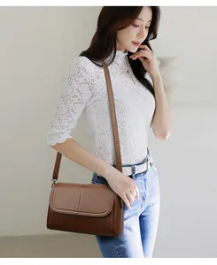 Borsa a tracolla in pelle marrone con grana litchi e patta indossata dalla modella