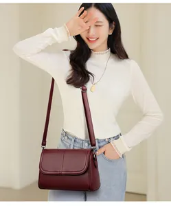 Borsa a tracolla in pelle rosso scuro con trama litchi indossata da una modella