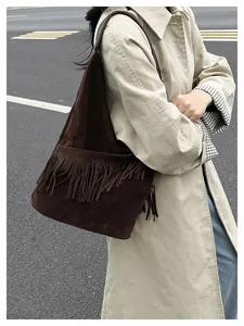 Dettaglio di una borsa tote in pelle scamosciata marrone scuro con lunghe frange