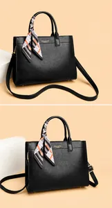 Dettaglio borsa tote in pelle nera a grana con sciarpa di seta decorativa sul manico