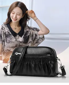 Close-up of black leather shell bag with pleated texture and silver zipper detail
