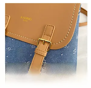Detailed close-up of brown leather flap with gold buckle and bear print denim fabric