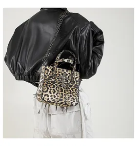Detail of leopard print tote bag with metallic studs, chain strap and cross pendant