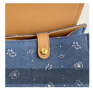 Detail of blue denim backpack with teddy bear print and golden magnetic buckle