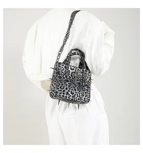 Detail of leopard print tote bag featuring silver studs and a metallic cross charm