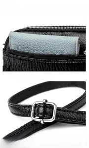 Detail of black leather shell bag showing smooth top zipper and adjustable silver buckle