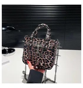 Detail of leopard print tote bag with silver studs, cross pendant and metal chain accents