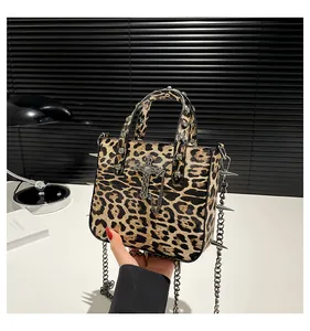 Macro view of leopard print tote featuring gothic metal cross and punk rivet details