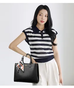 Dettaglio borsa tote in pelle nera con foulard di seta decorativo sul manico e logo