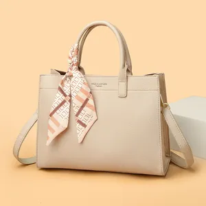 Dettaglio della borsa tote beige in pelle con foulard decorativo e tracolla regolabile