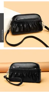 Detail of black leather crossbody bag with pleated texture and silver hardware accents