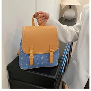 Detail of blue denim backpack with cute bear patterns and brown leather buckle flap