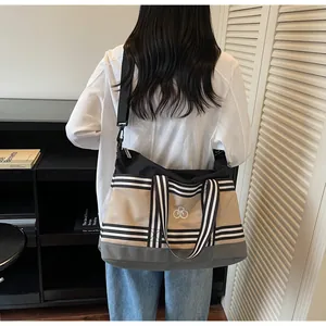 Detail of multi-color canvas travel bag with wide black strap and striped design