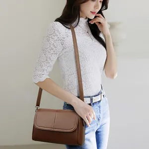 Borsa a tracolla in pelle marrone con texture litchi indossata da modella in ambiente interno