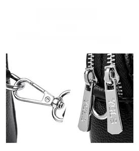 Detail of black lychee leather bag featuring polished silver zippers and spring hooks